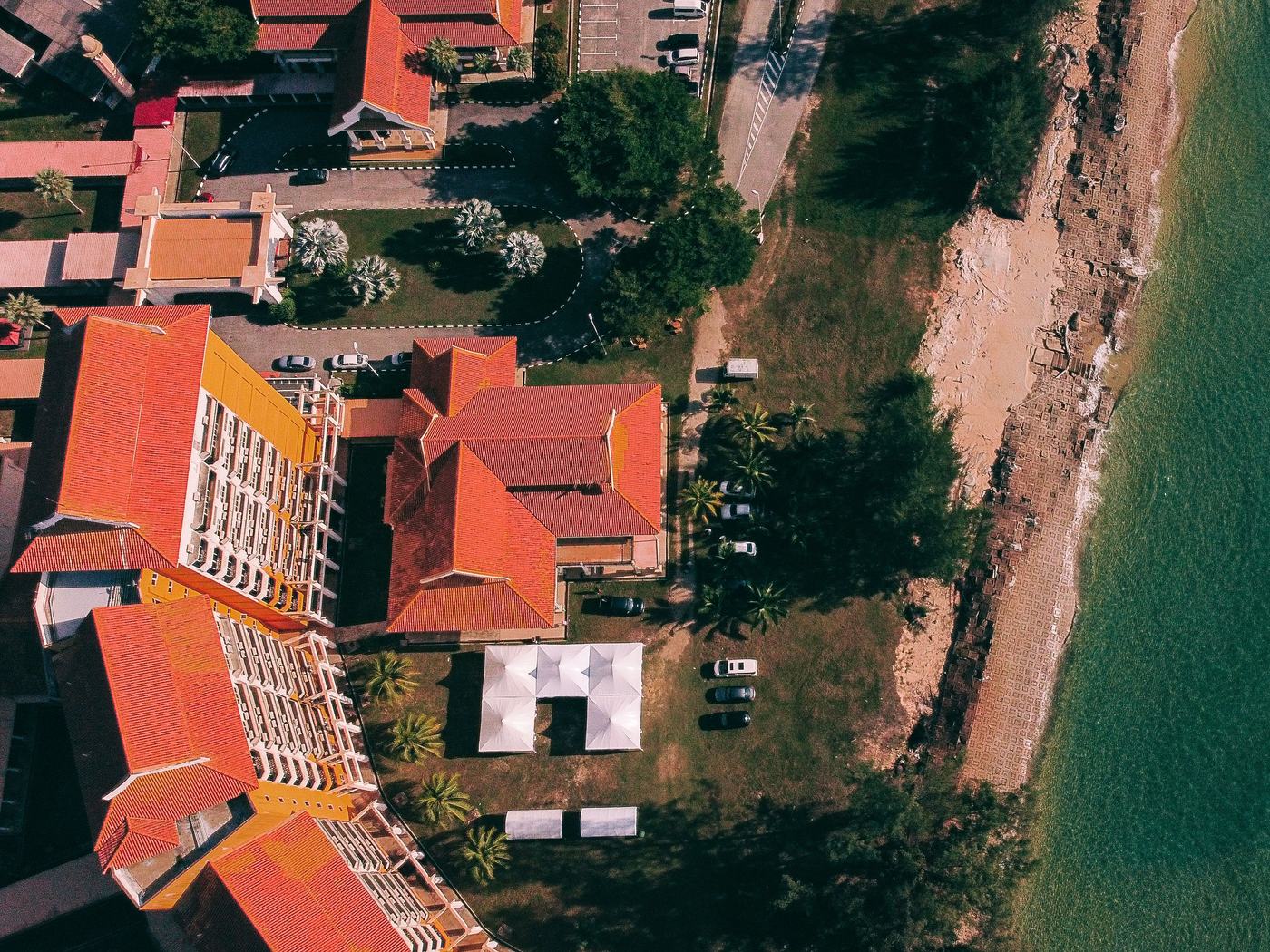 Aerial view along a resort beachfront, hotels and pools on the shoreline beside the sea